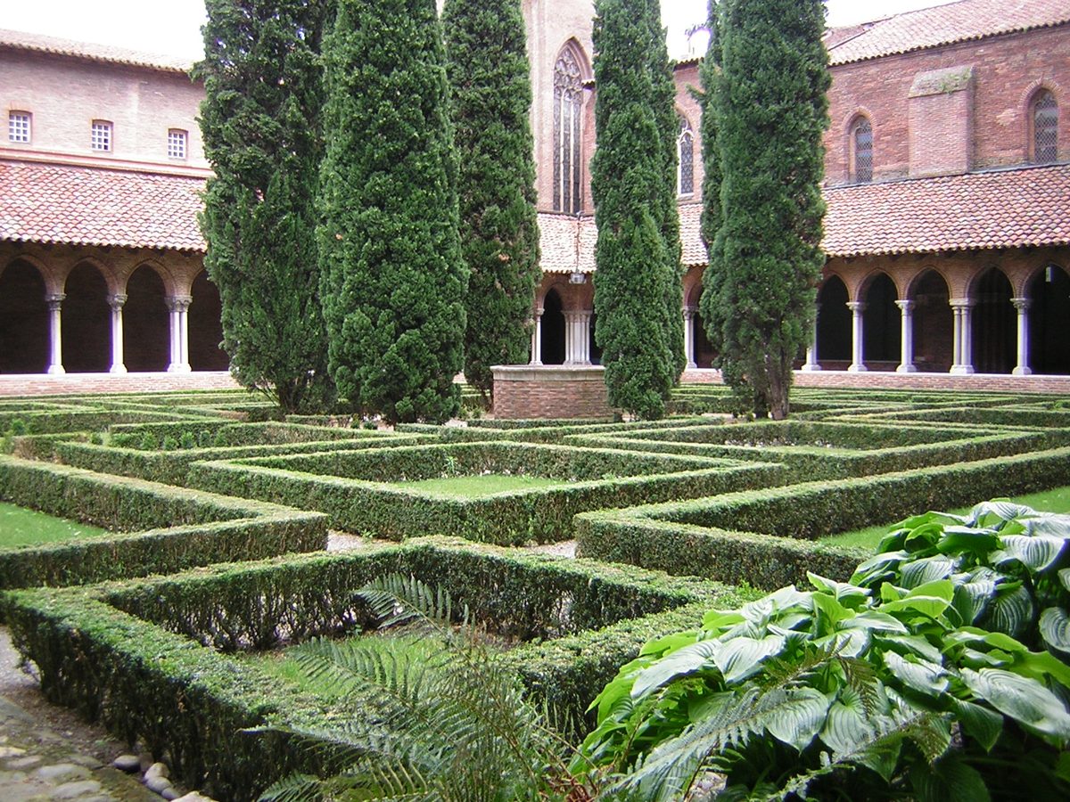 Bordaduras baixas de buxinho aparadas formando canteiros geométricos num claustro